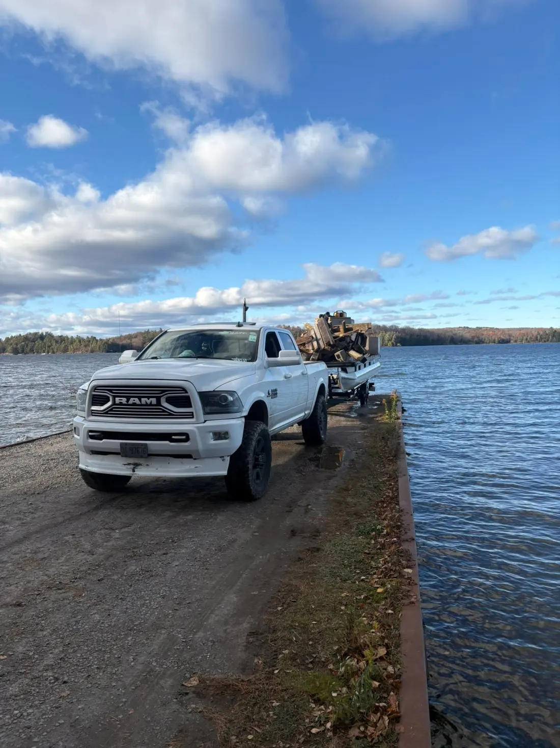 Crofty's Plumbing truck and loaded boat trailer at a Muskoka boat launch, hauling materials off-shore